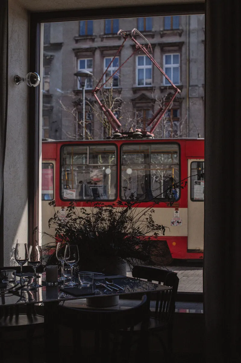 Röd spårvagn passerar utanför ett restaurangfönster i Dolne Miasto, Gdańsk